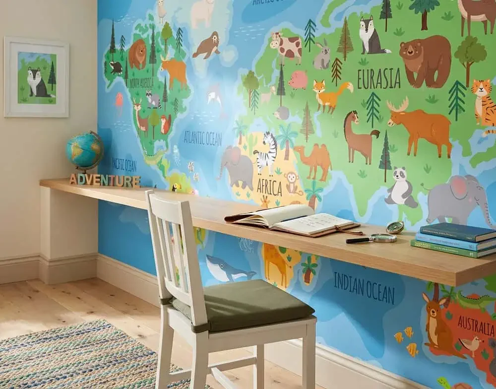 wereldkaart behang dieren achter lang bureau en boeken in kinderkamer